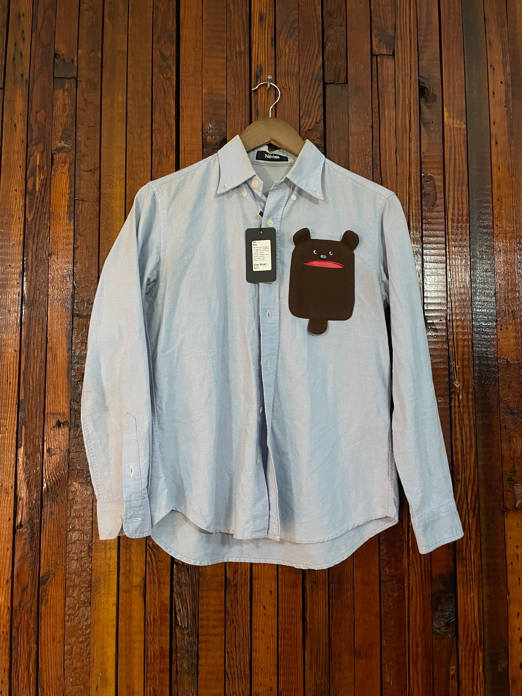 Light blue shirt with a bear design on a wooden surface